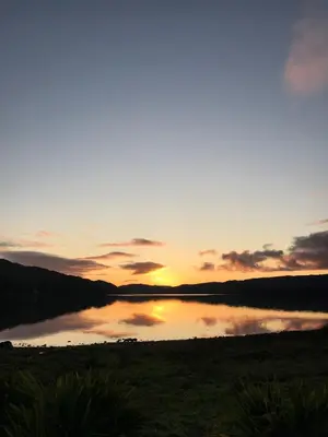 a sunset over a lake with the sun setting at Taychreggan, Signature Collection by Eight Continents in Oban