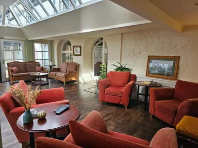 a living room with red chairs and tables at Taychreggan, Signature Collection by Eight Continents in Oban