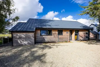 a house with a metal roof on top of a driveway at New Build Lodge With Stunning Views of Loch Awe in Hayfield