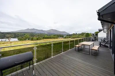 a deck with two benches and a table on it at New Build Lodge With Stunning Views of Loch Awe in Hayfield