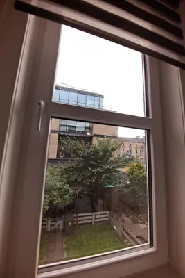 a window with a view of a tree and a building at Cosy one bedroom flat in city center in Edinburgh