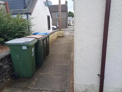 a row of trash cans on a sidewalk next to a building at Viewlands house in Auchterarder