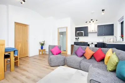 a living room with a gray couch with colorful pillows at Shiphorns luxury cabin with a hot tub in Eddleston