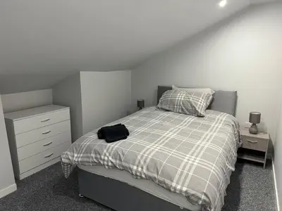 a bedroom with a bed with a plaid blanket and a dresser at Nelson st (YELL) in Largs