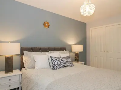 a bedroom with a white bed with two lamps and two tables at Greystones Cottage in Crieff