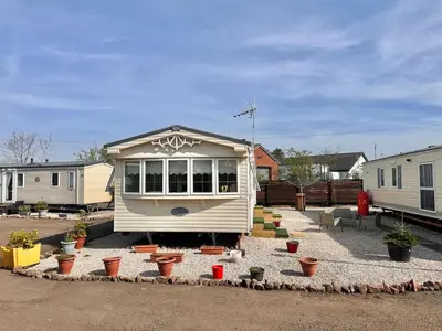a tiny house in a yard with potted plants at Willerby Granada 2-Bedroom Located in Uddingston, Glasgow at Maryville Caravan Site in Uddingston