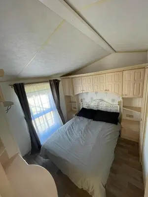 a bed in a small room with a window at Willerby Granada 2-Bedroom Located in Uddingston, Glasgow at Maryville Caravan Site in Uddingston