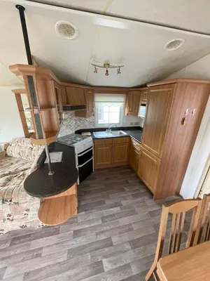 an rv kitchen with wooden cabinets and a table at Willerby Granada 2-Bedroom Located in Uddingston, Glasgow at Maryville Caravan Site in Uddingston