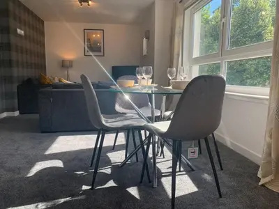 a dining table and chairs in a living room at Modern 2 bedroom flat with free parking in Cambuslang, Glasgow in Glasgow