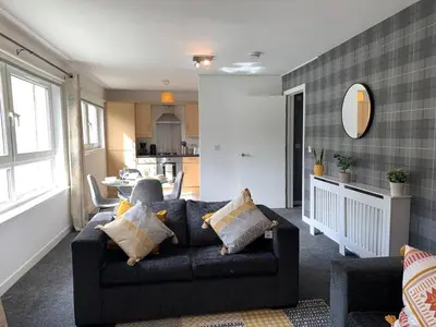 a living room with a couch and a kitchen at Modern 2 bedroom flat with free parking in Cambuslang, Glasgow in Glasgow