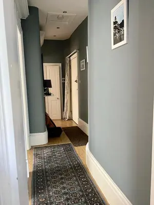 a hallway with green walls and a rug on the floor at Beautiful Double Room in Idyllic West End Townhouse in Glasgow