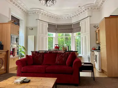 a living room with a red couch and a window at Beautiful Double Room in Idyllic West End Townhouse in Glasgow