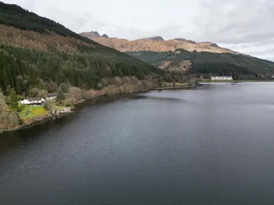 arial view of a lake with mountains in the background at WATERSIDE 3 BED COTTAGE, HOT TUB, SAUNA, PVT BEACH in Arrochar