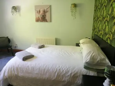 a bedroom with a white bed with a dog picture on the wall at WATERSIDE 3 BED COTTAGE, HOT TUB, SAUNA, PVT BEACH in Arrochar