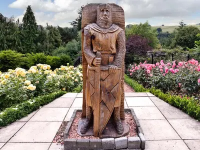 a statue of a man standing in a garden at Castlegate in Lanark