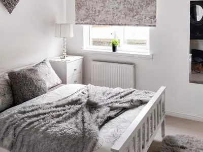 a bedroom with a bed with a blanket and a window at Castlegate in Lanark