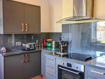 a kitchen with granite counter tops and a stove top oven at Kirklea in Wishaw
