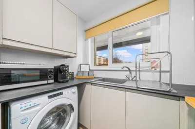 a kitchen with a washing machine and a sink at One Bed Holiday Home in the Heart of Glasgow in Glasgow