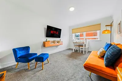 a living room with an orange couch and a tv at One Bed Holiday Home in the Heart of Glasgow in Glasgow