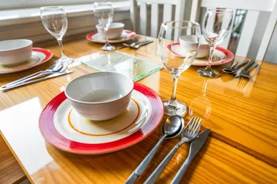 a wooden table with plates and wine glasses on it at One Bed Holiday Home in the Heart of Glasgow in Glasgow