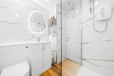 a white bathroom with a shower and a mirror at One Bed Holiday Home in the Heart of Glasgow in Glasgow