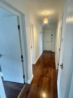 an empty hallway with a white door and wooden floors at Modern 2 bedroom apartment near Glasgow Airport in Paisley