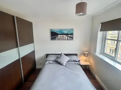 a bedroom with a bed and a large window at Modern 2 bedroom apartment near Glasgow Airport in Paisley