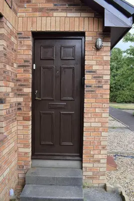 a brown door on the side of a brick building at Kelpies Serviced Apartments- McLaughlan in Falkirk