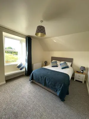 a bedroom with a large bed and a window at Cozy 2 bedroom cottage with log burner close to Loch Ken in New Galloway