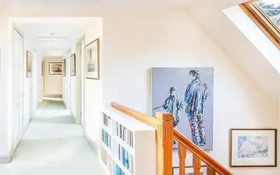 a hallway with white walls and stairs with paintings on the wall at The Stables in Castle Douglas