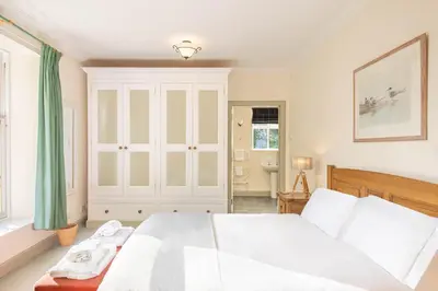 a bedroom with a white bed and a window at The Stables in Castle Douglas