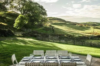 a table with white chairs and plates on a field at Blairinnie in Castle Douglas