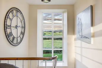 a clock on a wall next to a window at Blairinnie in Castle Douglas