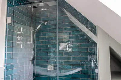 a bathroom with a shower with blue tiles at Culdoach in Castle Douglas
