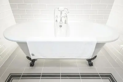 a white bath tub in a white tiled bathroom at Diamonds Laggan in Castle Douglas
