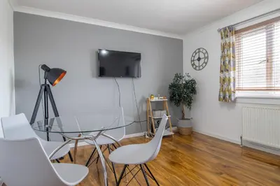 a dining room with a glass table and white chairs at 1 bed apartment central Hamilton free wifi with great transport links to Glasgow in Hamilton