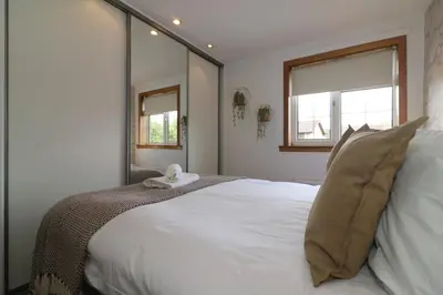 a bedroom with a large white bed with two windows at Signature - Binnie House in Cumbernauld