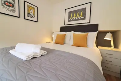 a bedroom with a large white bed with orange pillows at Signature - Binnie House in Cumbernauld