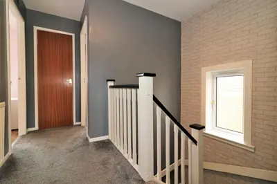 a hallway with a staircase and a window at Signature - Binnie House in Cumbernauld