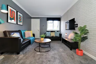 a living room with couches and a table and a tv at Signature - Binnie House in Cumbernauld