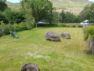 a park with rocks and a bench in the grass at Beautiful Farm House at the foot of Ben More. in Crianlarich