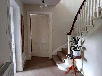 a hallway with stairs with a potted plant at Beautiful Farm House at the foot of Ben More. in Crianlarich