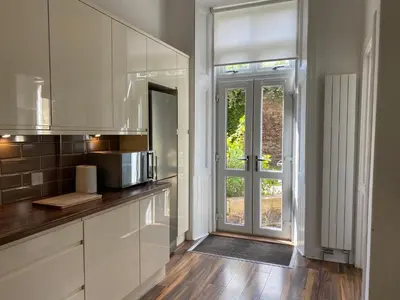 a kitchen with white cabinets and a door with a window at Lovely main door 2 bed apartment in Edinburgh