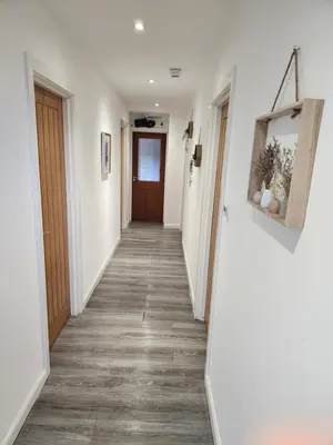 a hallway with white walls and a wooden door at Crosskeys Edinburgh in Edinburgh