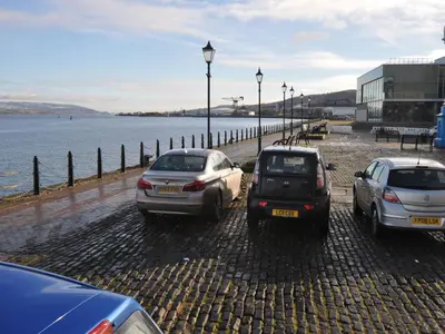 a group of cars parked next to the water at The Waterfront in Greenock