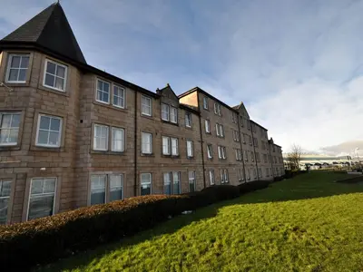 a large brick building with a grass field in front of it at The Waterfront in Greenock