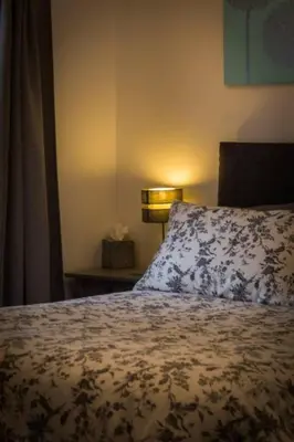 a bedroom with a bed with a pillow and a lamp at Ideal Couples base for exploring the Isle of Arran in Shiskine