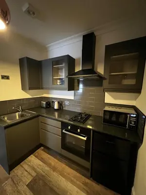 a kitchen with black cabinets and a stove and a sink at Amani Apartments - Glasgow City Centre in Glasgow