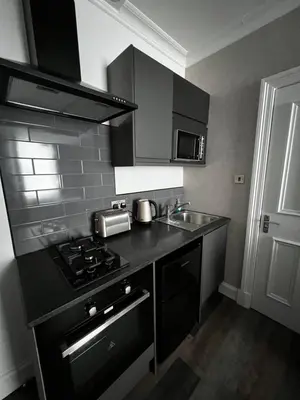 a kitchen with a black stove and a sink at Amani Apartments - Glasgow City Centre in Glasgow
