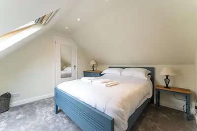 a bedroom with a blue and white bed and a mirror at Garden Cottage in Gargunnock